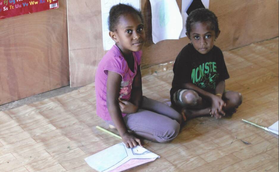 Two pupils drawing the Vanuatu flag on used paper