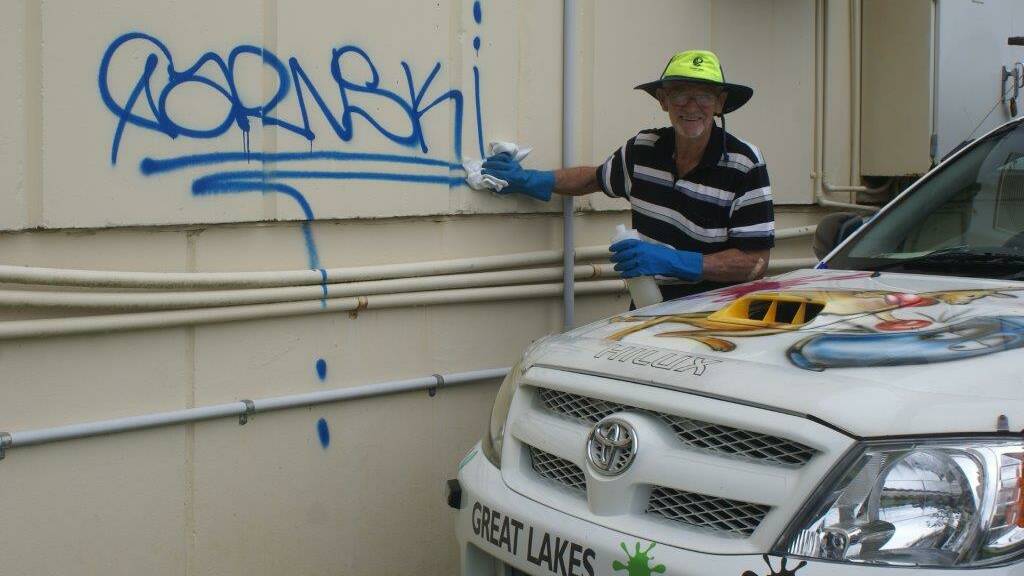 PASSING ON HIS KNOWLEDGE: Graffiti buster Ted Bickford demonstrates the removal of graffiti from a public building in Port Macquarie. Hastings Council is looking at implementing a graffiti program similar to the one Mr Bickford has established here in the Great Lakes.  
 