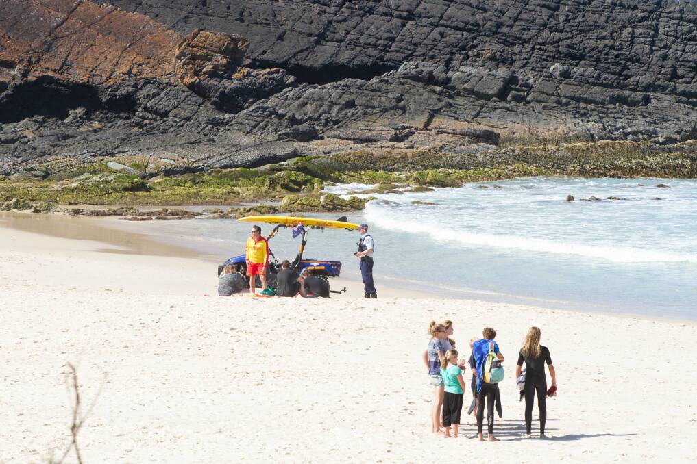 LUCKY ESCAPE: A police officer questions some of the males from Sydney involved in last Tuesday’s rescue at One Mile Beach. Photo by Dan Kirkman – Something Visual.  