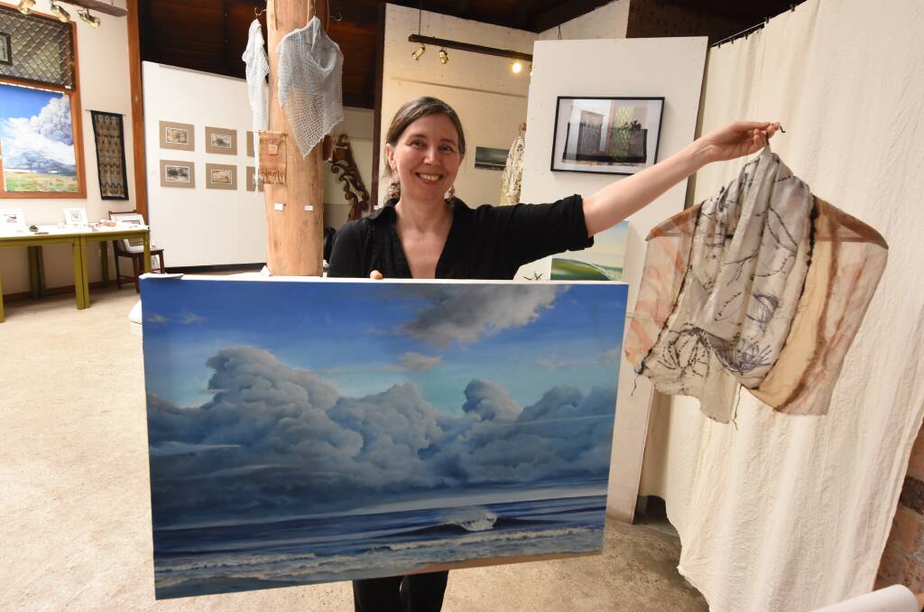 Summer holiday showcase: Jana Pearceova holds a painting by her husband Gerard and one of her textile works. Both are part of the exhibition currently showing at the Green Point Gallery. 
