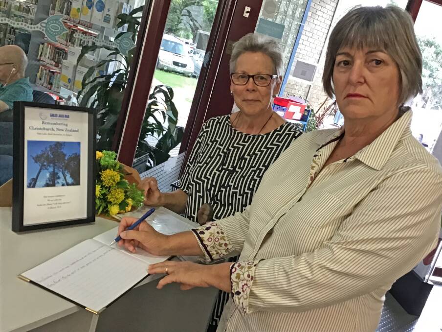Great Lakes Rural Australians for Refugees members, Margaret Gardner and Gaye Tindall sign the condolence book at Great Lakes Library.