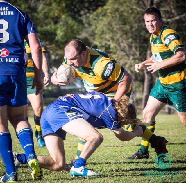 The Forster Tuncurry Dolphins front row forward, Gavin Maberly-Smith, drives the ball forward while attempting to break the tackle of the Wallamba Bulls breakaway, Rhys Hessing. Maberly-Smith will play for the Old Bar Clams this year with the Dolphins deciding to abandon the season. Patrick Randall is the supporting Dolphins forward.