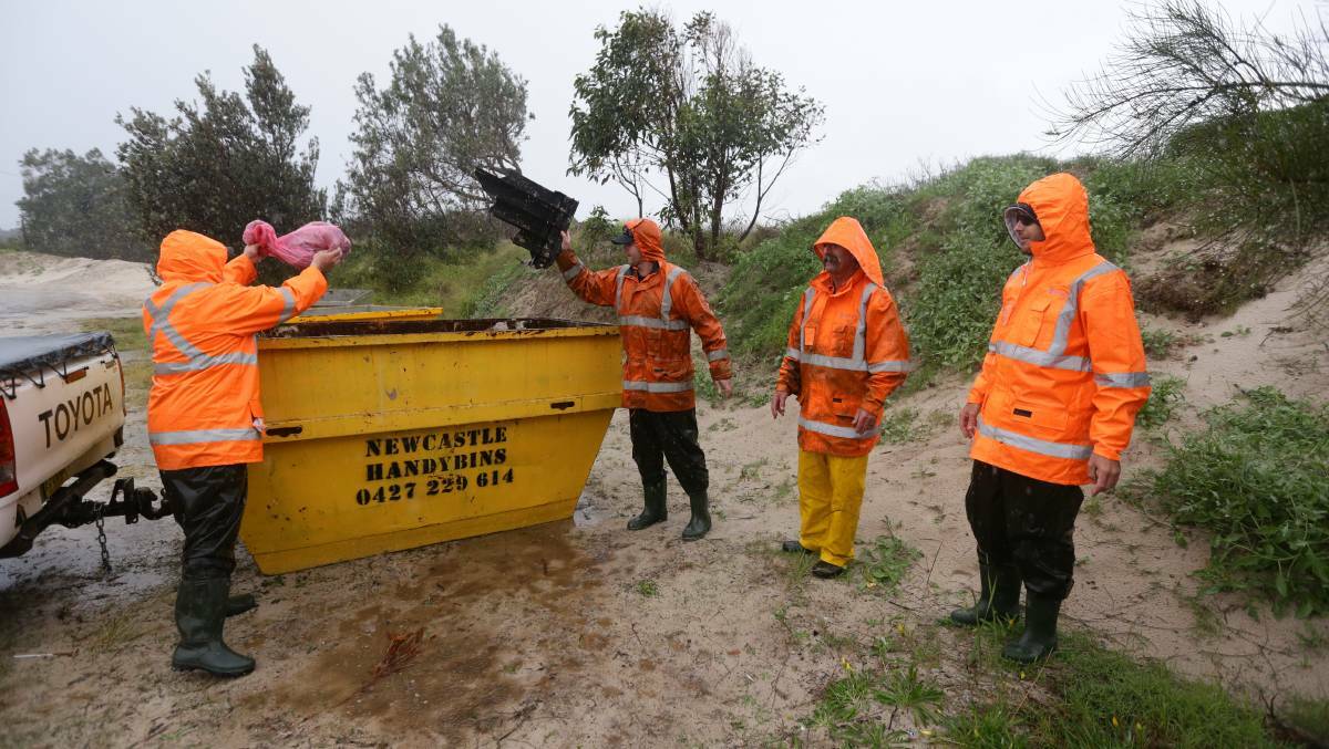 DEBRIS: Shipping containers have fallen off the back of a ship and the contents have been washing up on the beaches around Hawks Nest. Picture shows Varley employees cleaning up at Jimmy's Beach. Picture: Jonathan Carroll.