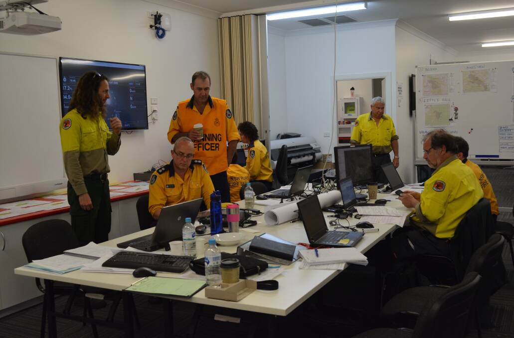 Planning cell: Team members from NPWS and NSW RFS discuss strategies for the fires. Photo: Anne Keen 