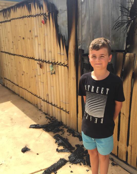 Little legend: Corbin Niblett standing beside the shed that was damaged in the fire.