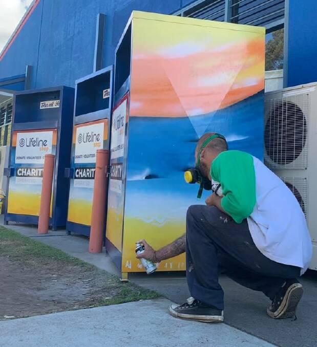 Forster artist Adam Murray applying some life and colour to the bins outside the Forster Lifeline Shop.