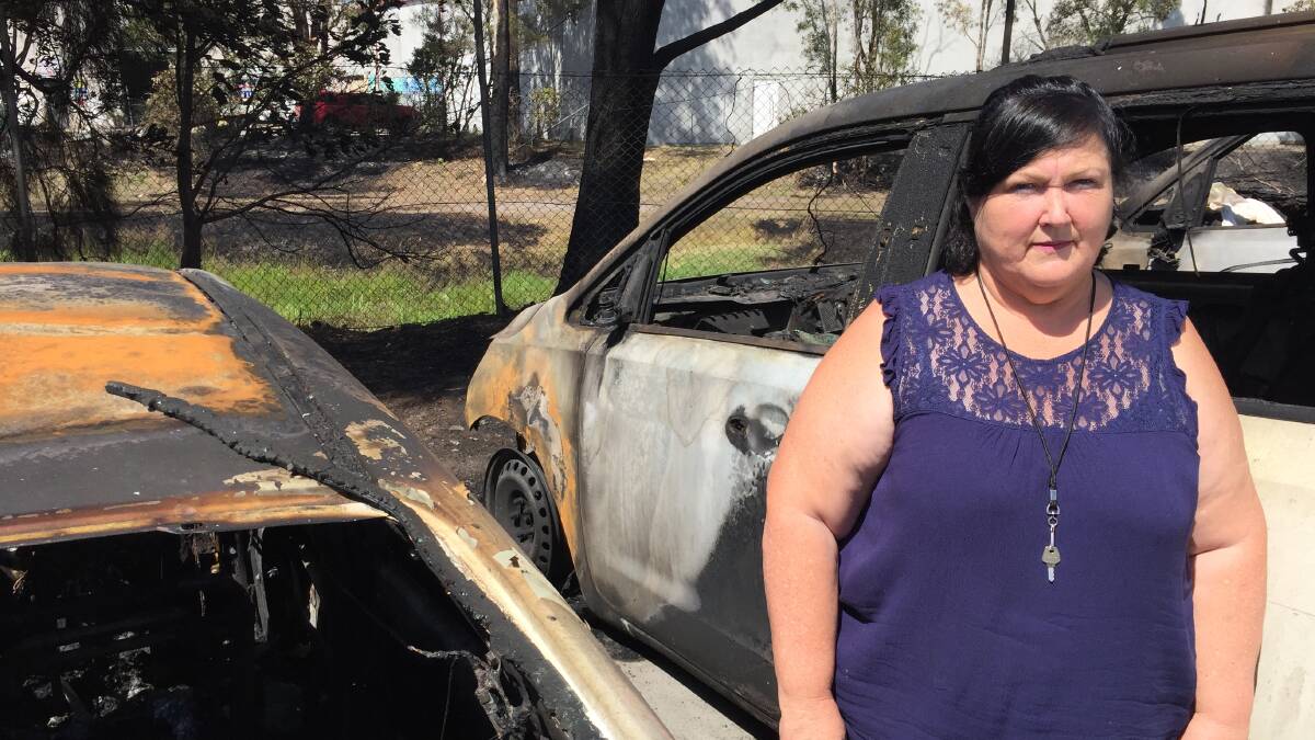 Heather Smith of Lifestyle Solutions with the charred remains of two of their customer transport vehicles.