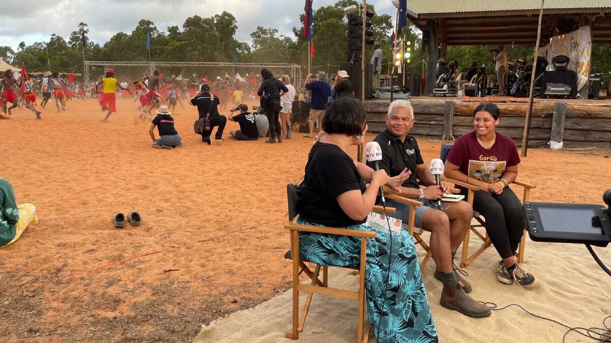 Amarley (right) being filmed on the NITV panel, with dancers on the Bunggul grounds in the background. Image supplied