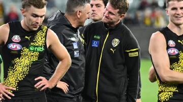 Richmond coach Adem Yze (second left) chats with an injured Jacob Hopper during the Melbourne game. (James Ross/AAP PHOTOS)