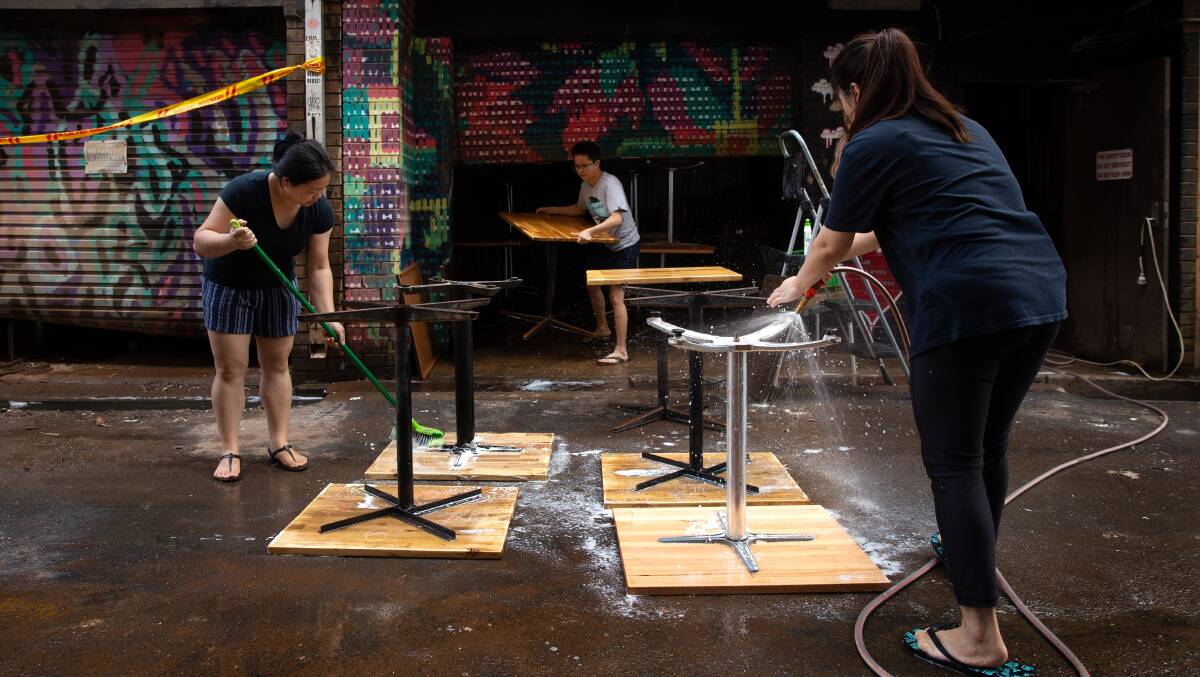 Athena Chan, Jia Mah and Wen Chua clean up their cafe after the second flood. The family only bought the business in December. 