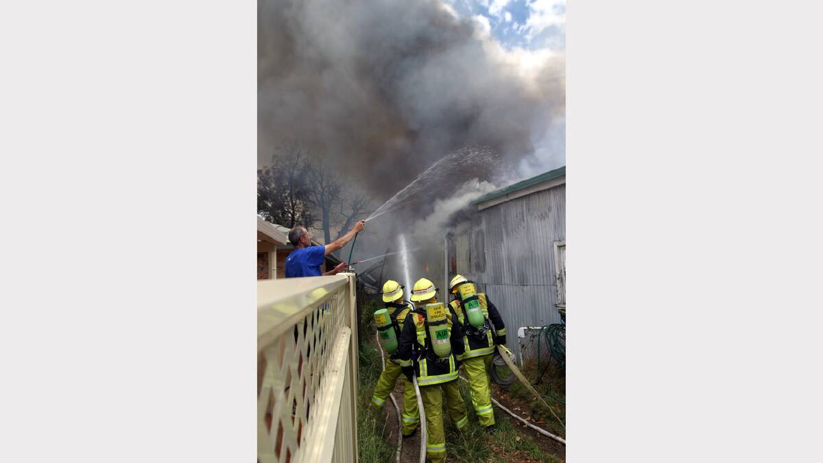 THROWBACK THURSDAY: Neighbours aim garden hoses at the blaze while firefighters drag in the "big guns" during Sunday's  fire at Lakesway Secondhand. 