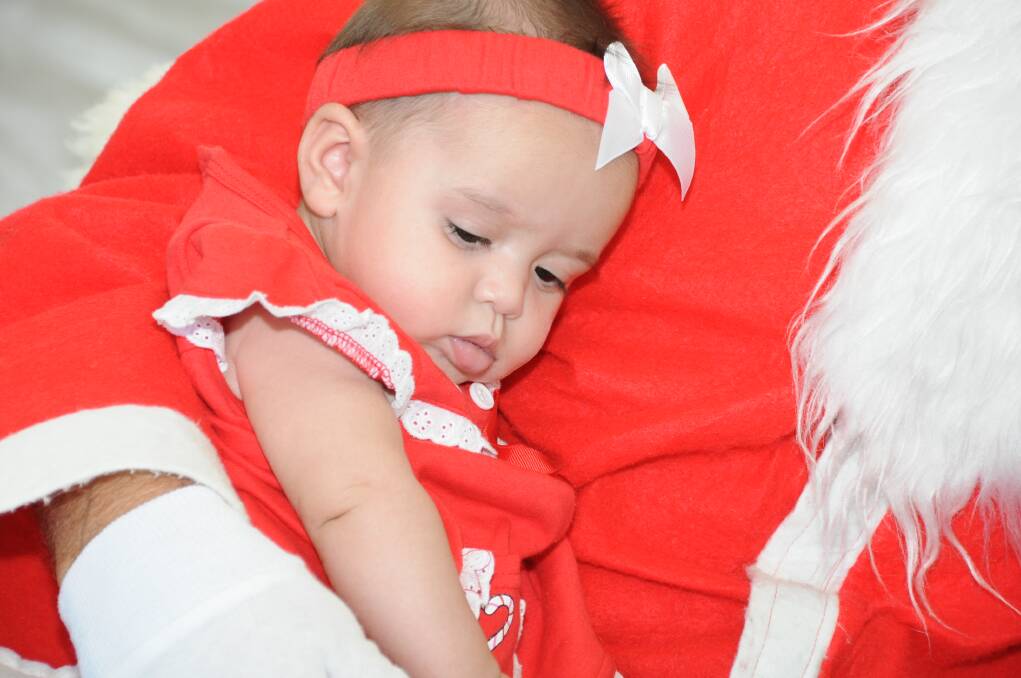 Amalia Perkins in the arms of Santa at the Taree Early Intervention Christmas party. Photo:The Manning River Times.